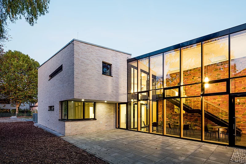 Eines der grundsanierten Häuser von HGP Architekten als Architekturbüro Offenbach. Das Gebäude ist sehr modern, die Wand teils weiß, teils komplett mit Fenstern bestückt. 