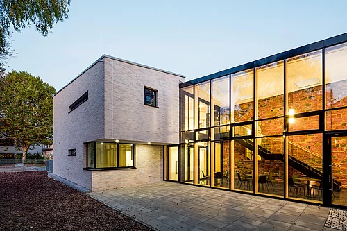 Eines der grundsanierten Häuser von HGP Architekten als Architekturbüro Offenbach. Das Gebäude ist sehr modern, die Wand teils weiß, teils komplett mit Fenstern bestückt. 
